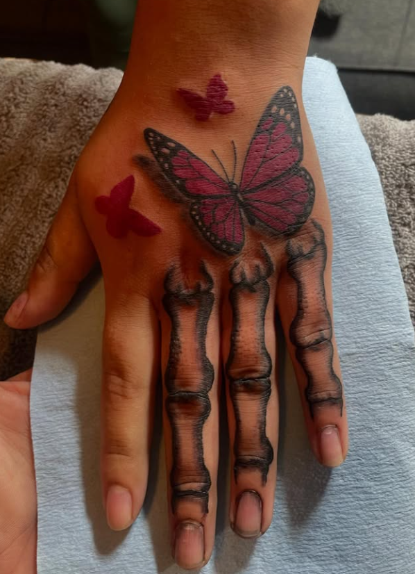 Hand tattoo with skeletal finger bones and pink butterflies