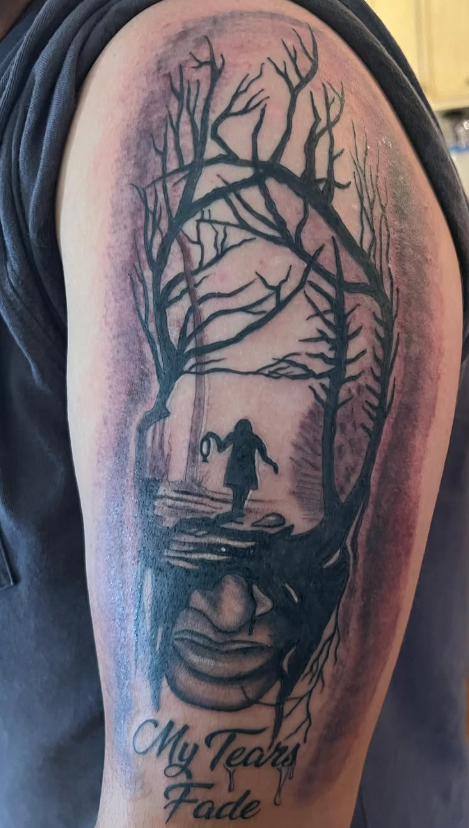 Arm tattoo of a silhouette in a forest with text 'My Tears Fade'