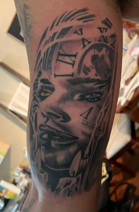 Arm tattoo of a woman's face with clock gears and Roman numerals