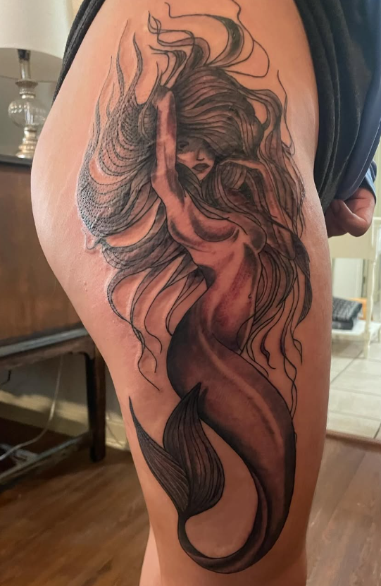 Black and grey thigh tattoo of a mermaid with long, flowing hair