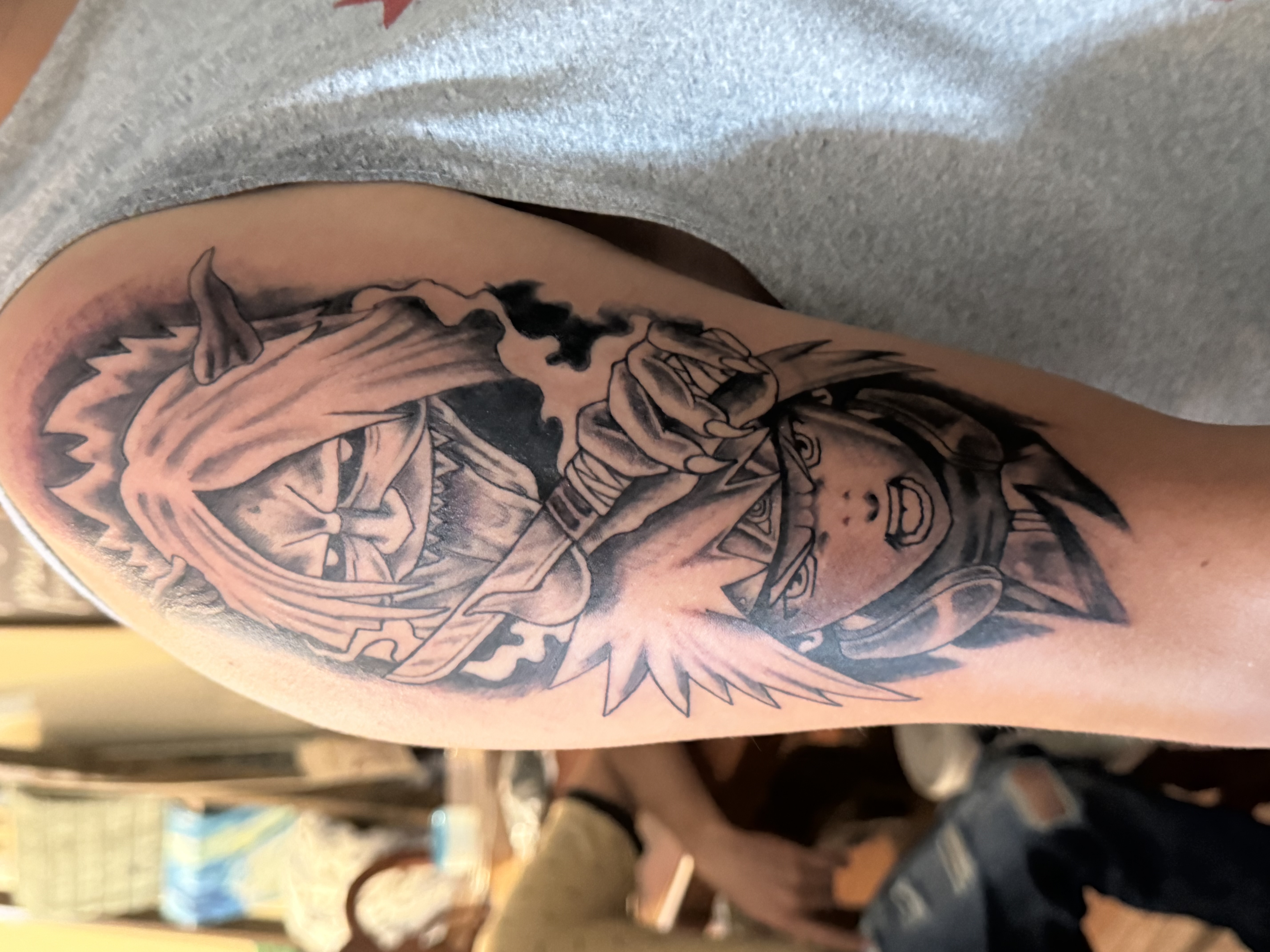 Black and grey arm tattoo featuring anime characters from Naruto