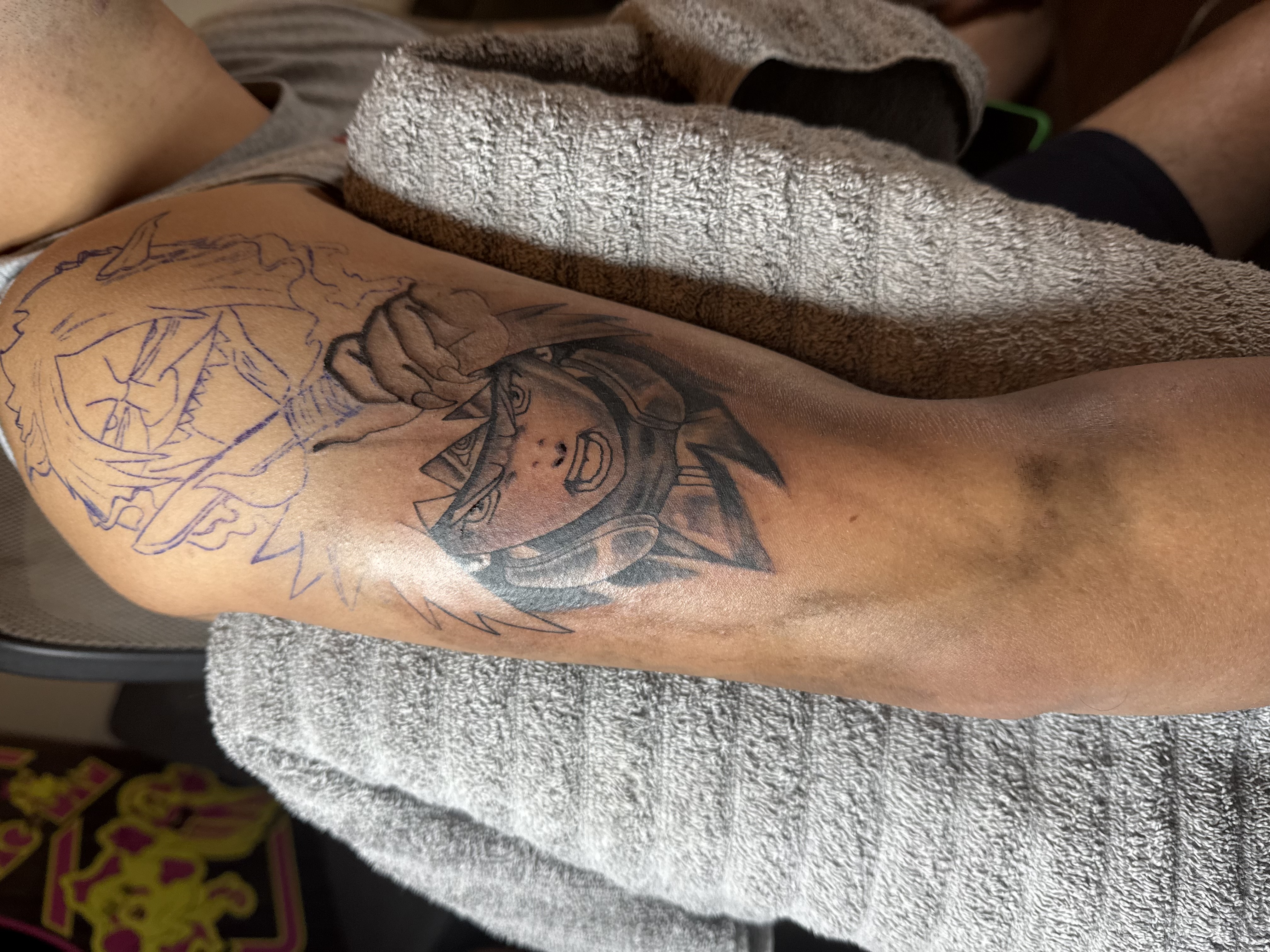 Naruto anime tattoo in progress showing outline and partial shading work