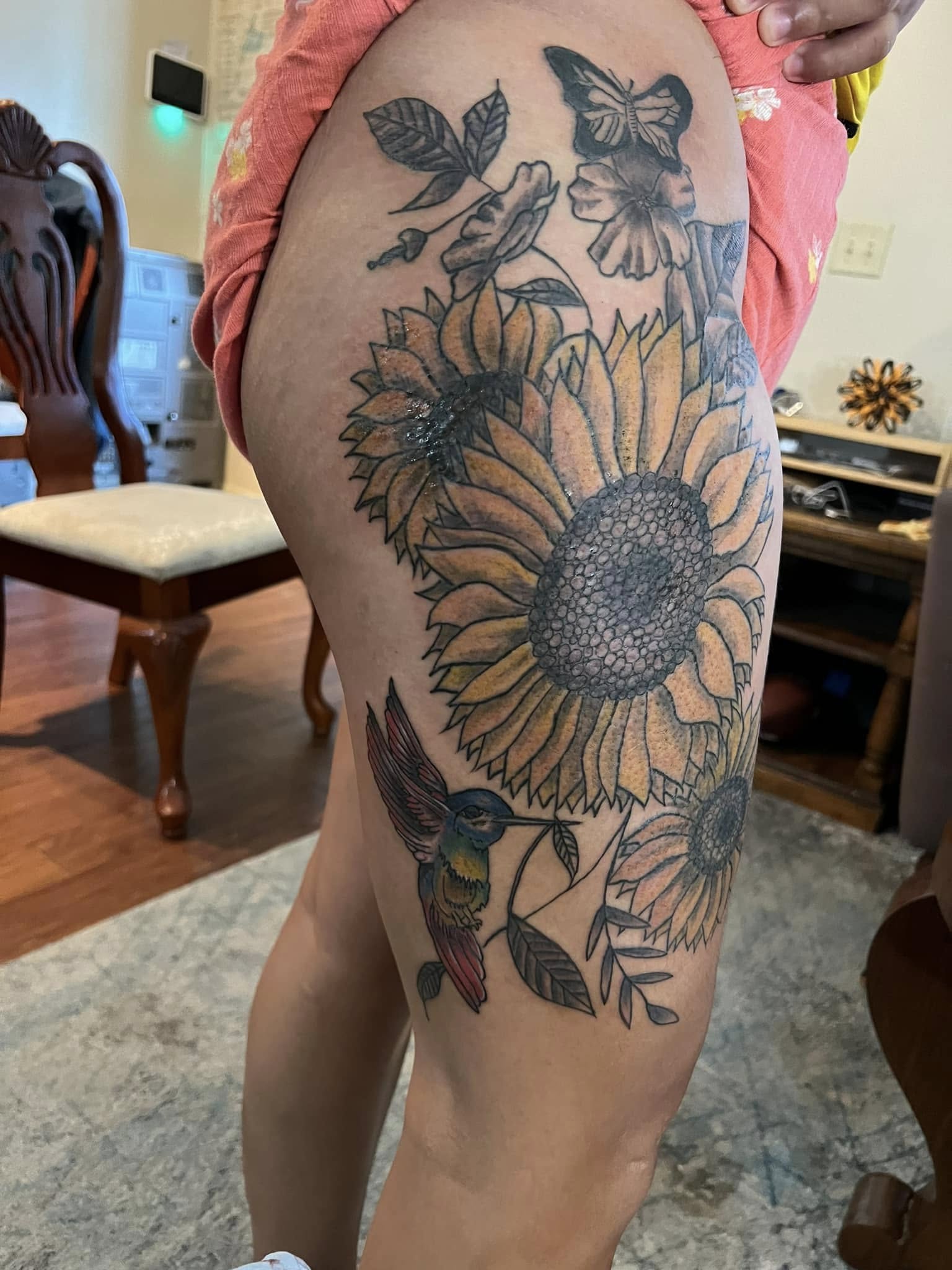 Sunflowers, hummingbird, and butterflies thigh tattoo